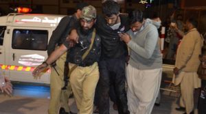 A Pakistani volunteer and a police officer rush an injured person to a hospital in Quetta, Pakistan, Monday, Oct. 24, 2016, after two separate attacks in Pakistan. Gunmen stormed a police training center in the restive southwestern province of Baluchistan Monday, leaving several people wounded, hours after another attack near to Quetta leaving two customs officers dead, authorities said. (AP Photo/Arshad Butt)